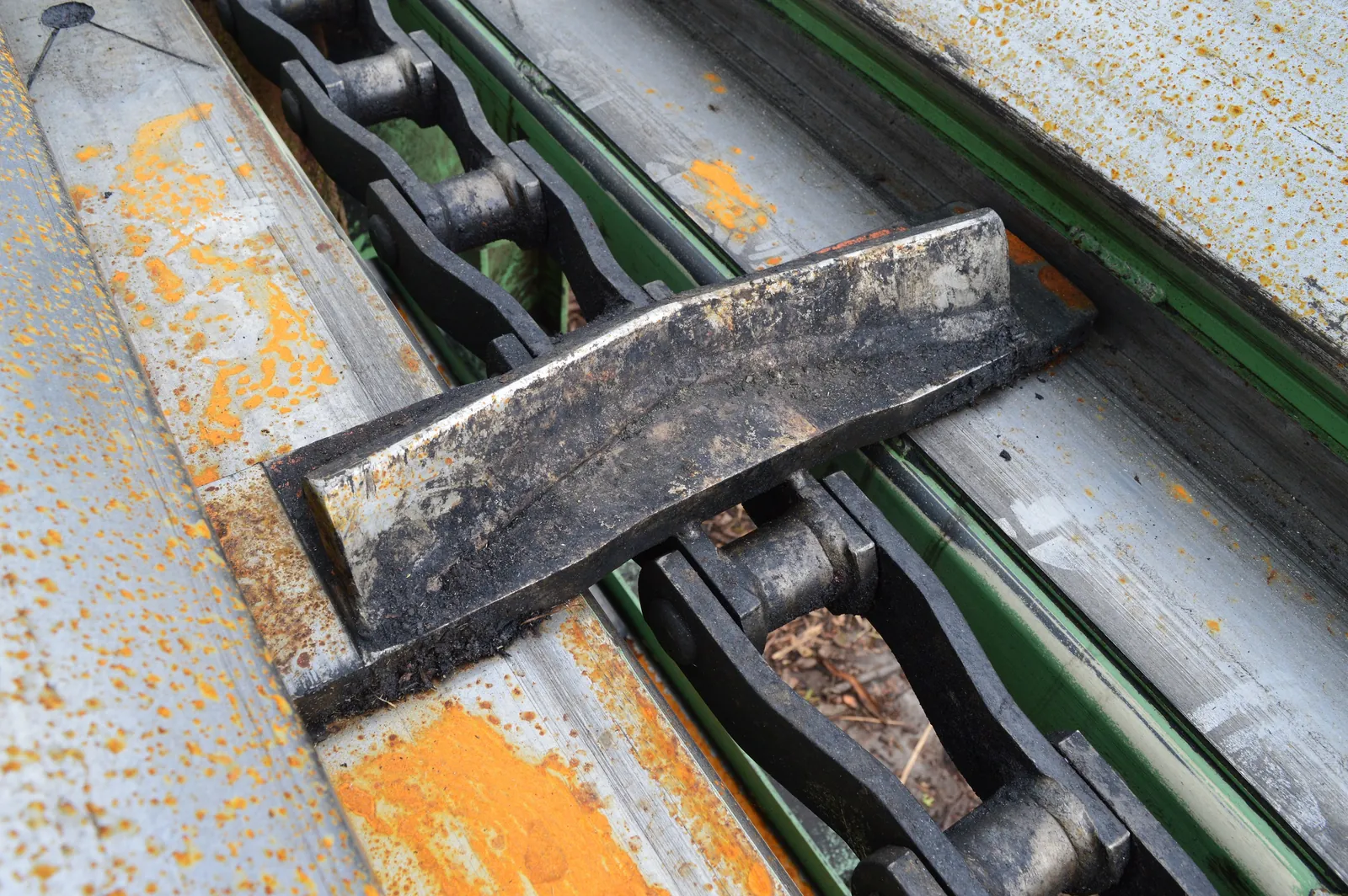Flat-bar scraper flight on drag conveyor chain at a sawmill waste line
