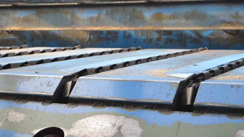 Transfer deck chain run with welded attachments carrying boards at a sawmill