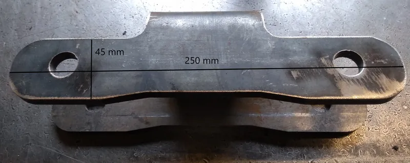 Worn welded steel chain link sidebar measured on the bench: 250 mm with 45 mm hole centres marked