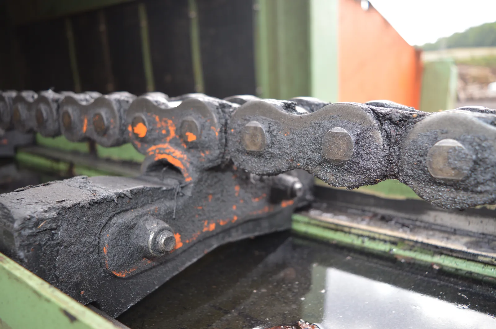Worn, dirt-caked conveyor chain riding over a worn cast sprocket wheel